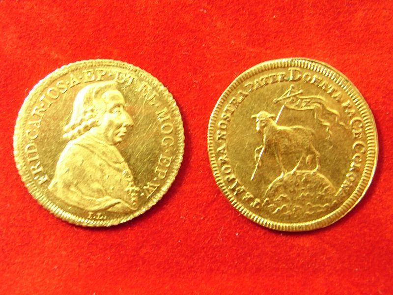 Zwei Goldmünzen auf einer roten Fläche, eine mit einem Mann darauf