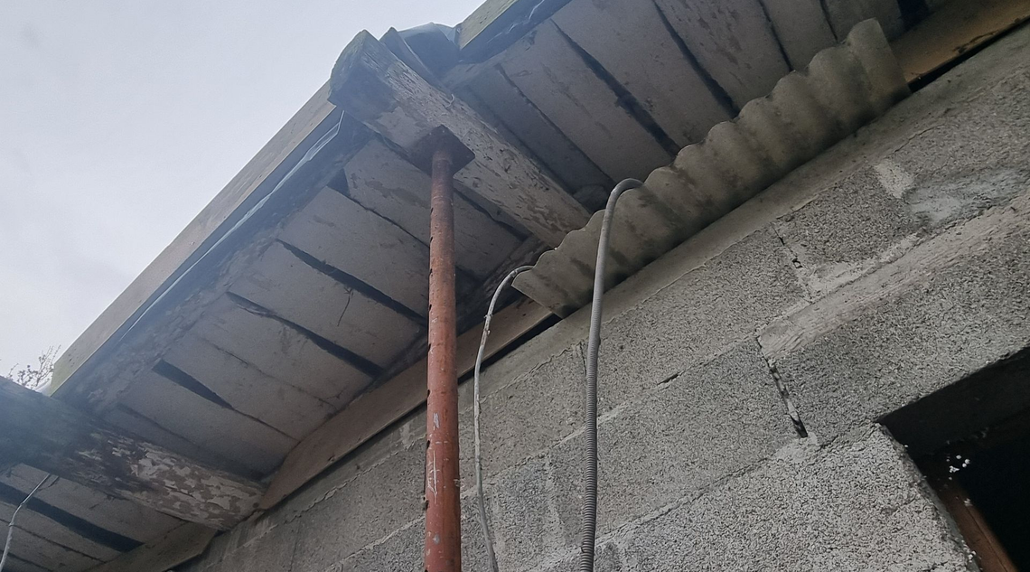 Le dessous d’une toiture en béton soutenue par un poteau métallique rouillé