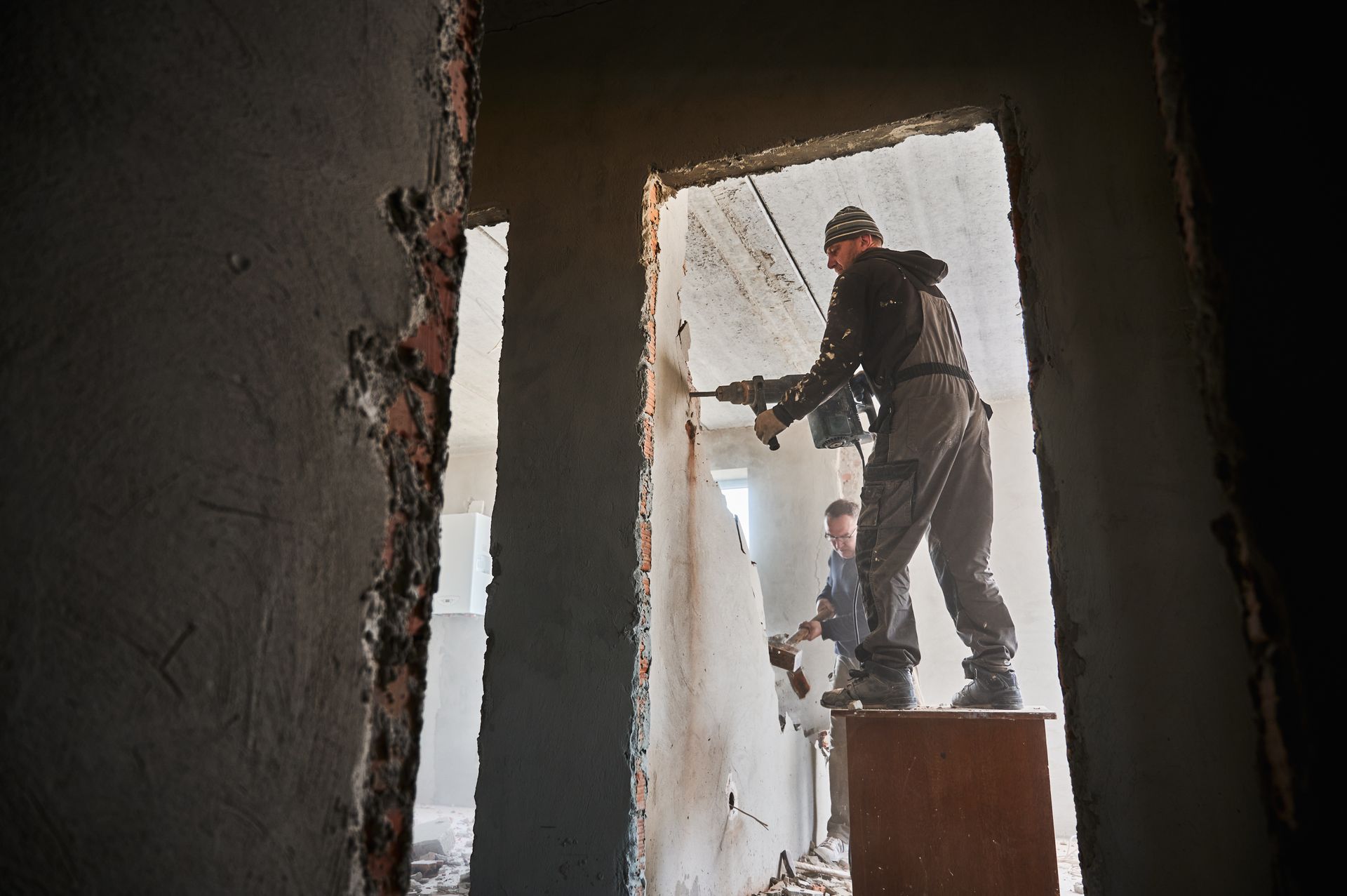 Des techniciens démolissent un mur porteur dans une habitation.