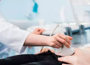 Persona con bata blanca realizando una ecografía abdominal a un paciente.