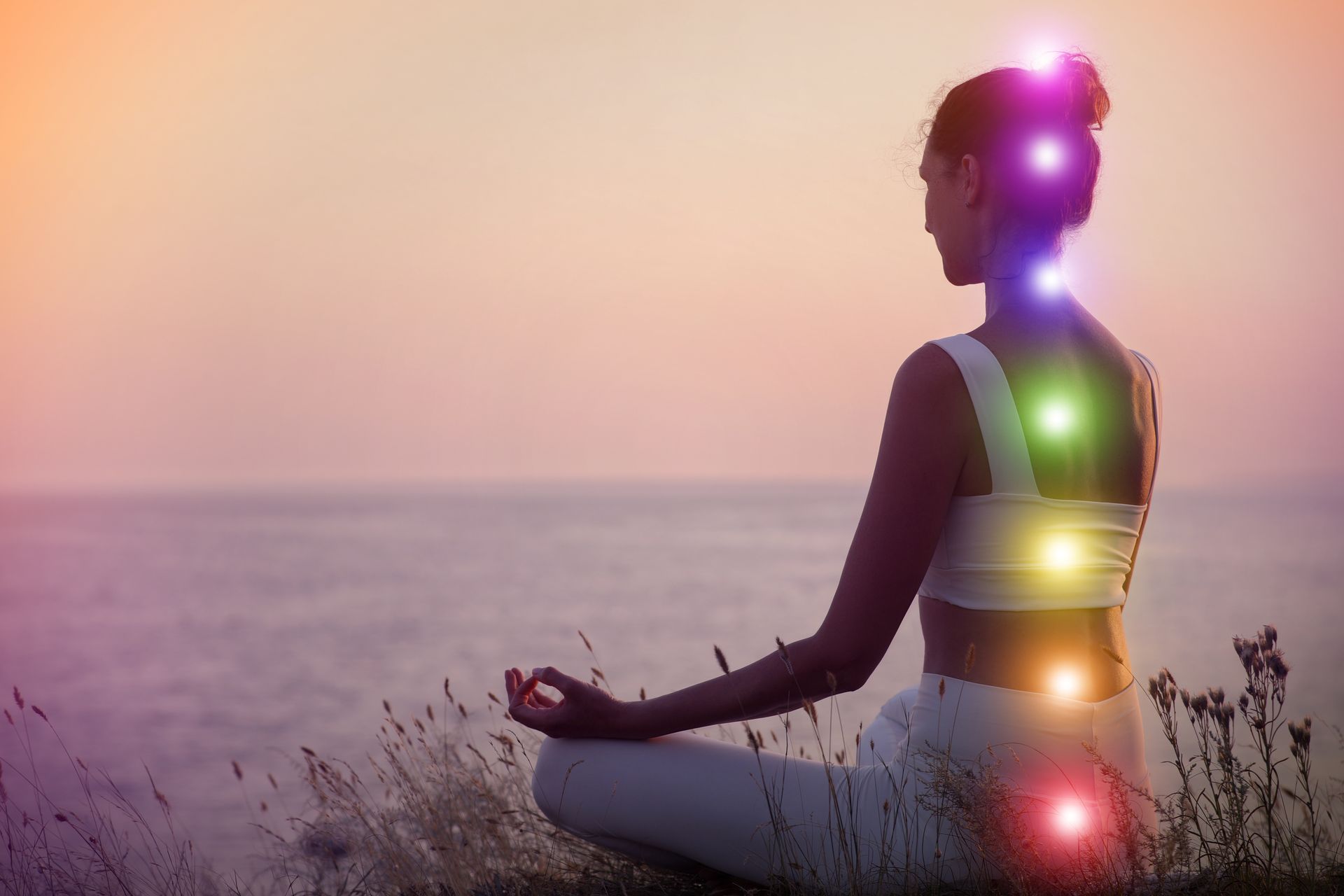 Une femme est assise en position du lotus avec les chakras dans le dos.