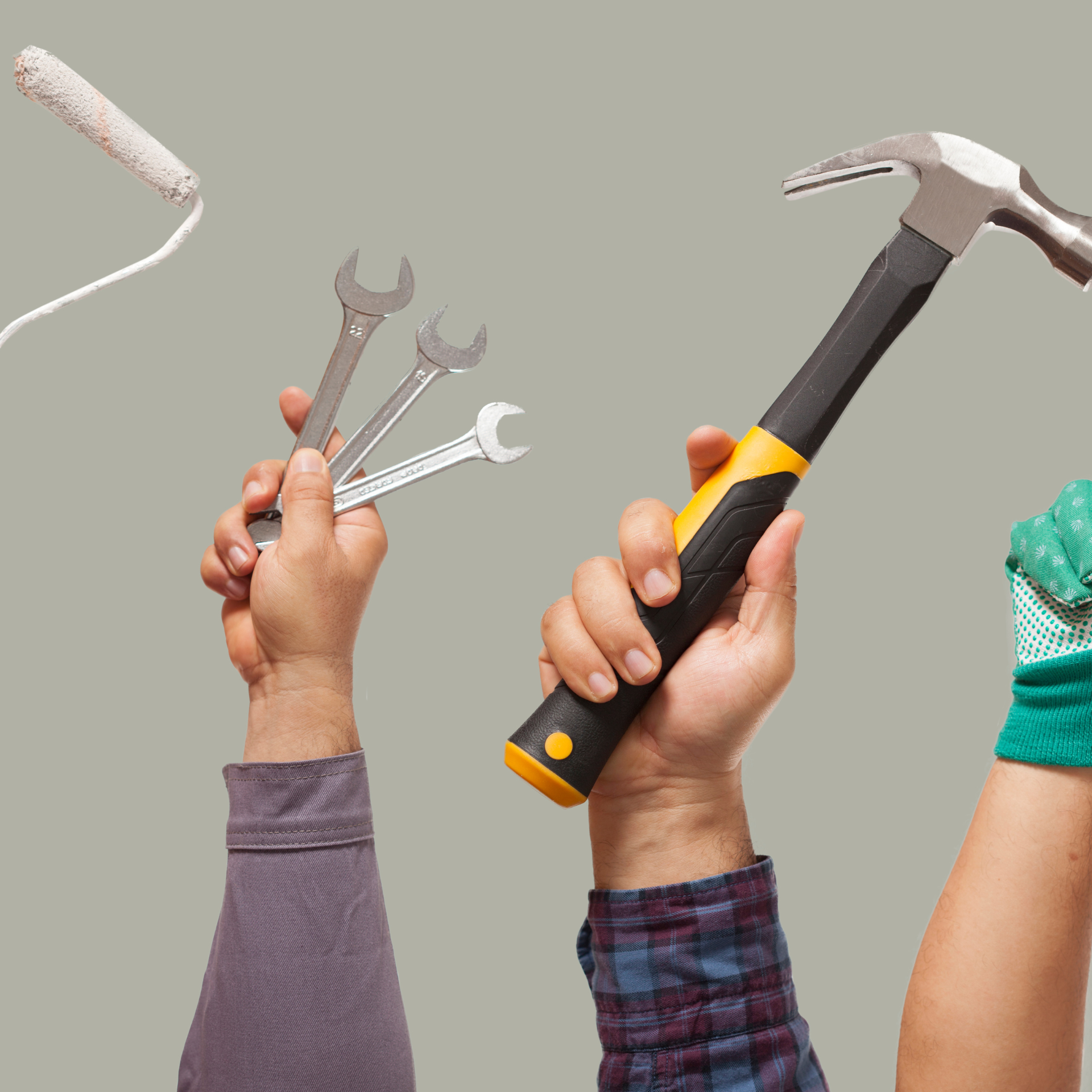 Une personne tient une clé et un marteau tandis qu'une autre personne tient un rouleau à peinture