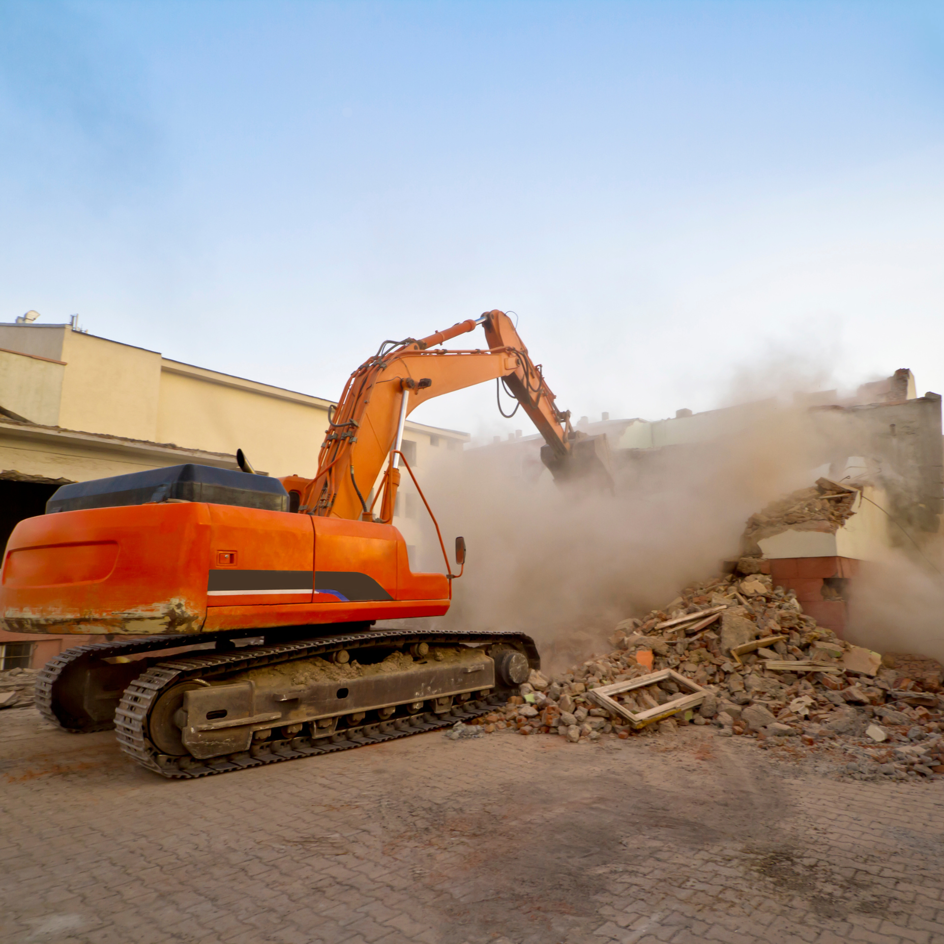 Une grande excavatrice orange démolit un bâtiment.