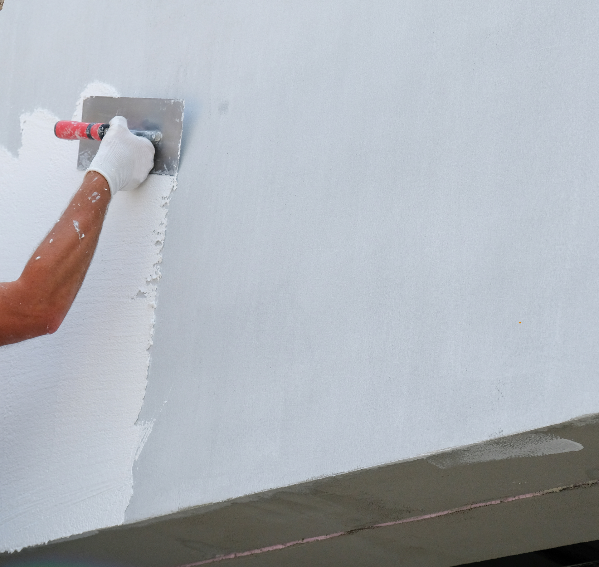 Une personne enduit un mur avec une truelle