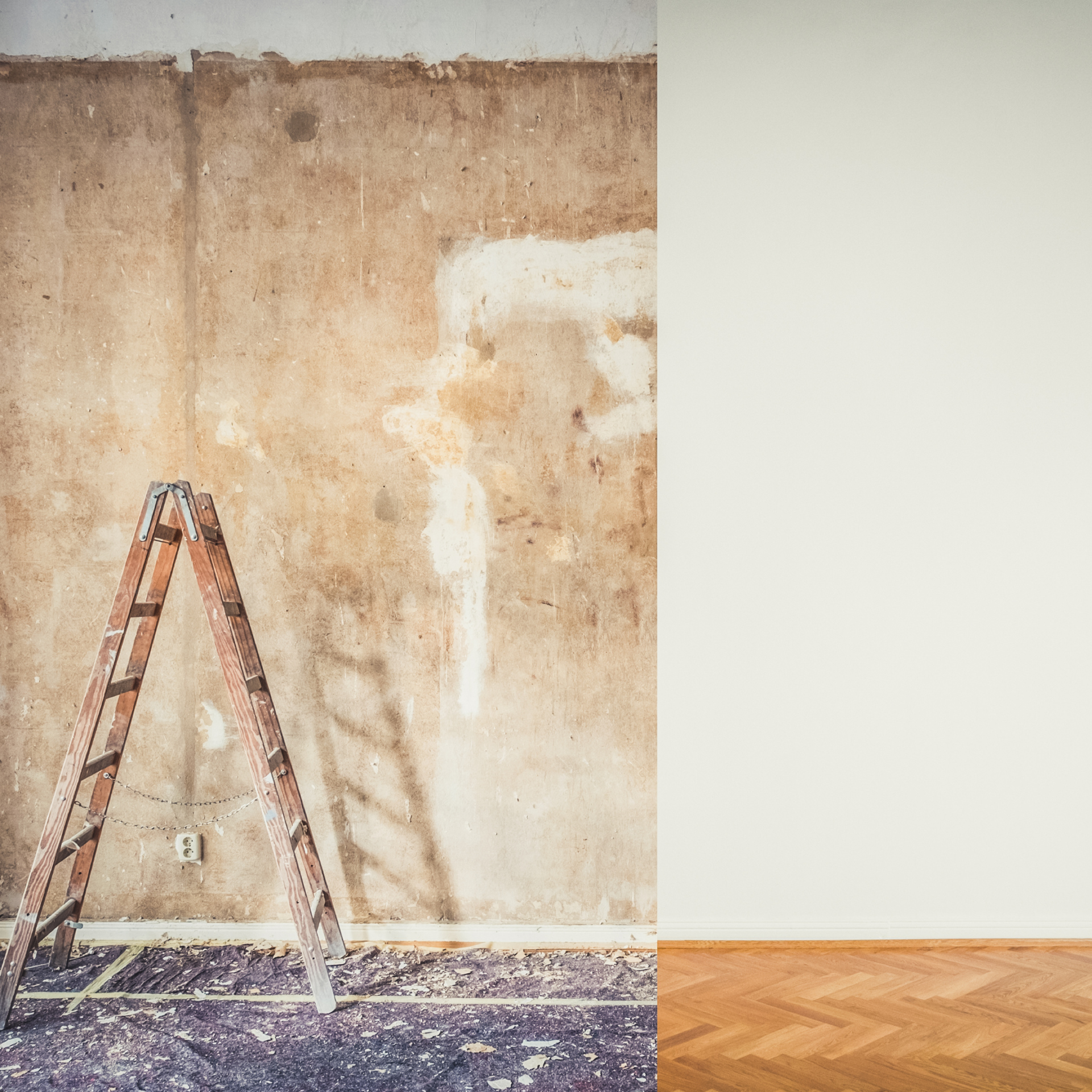 Une échelle en bois est appuyée contre un mur dans une pièce vide.