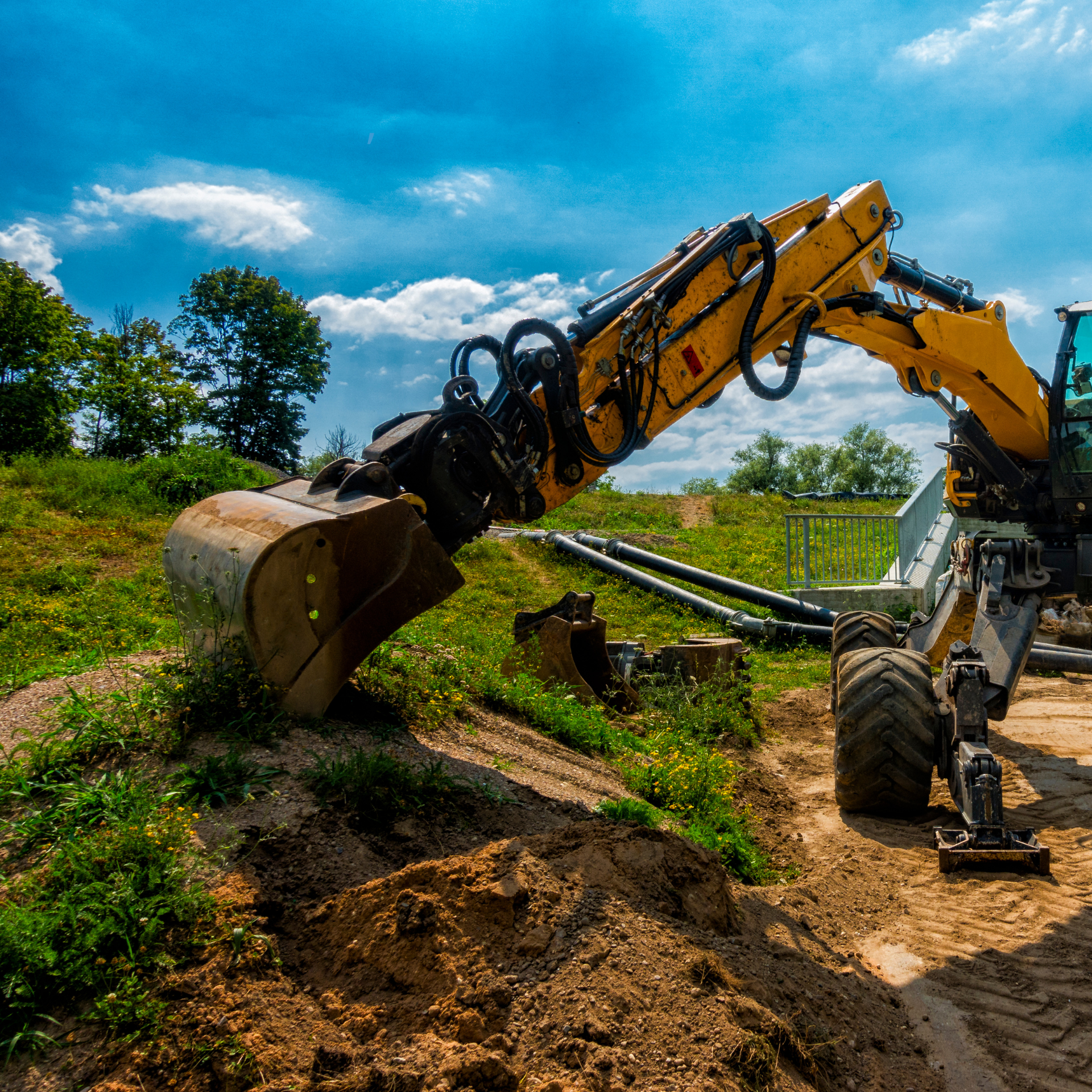 Une excavatrice jaune creuse un trou dans la terre.