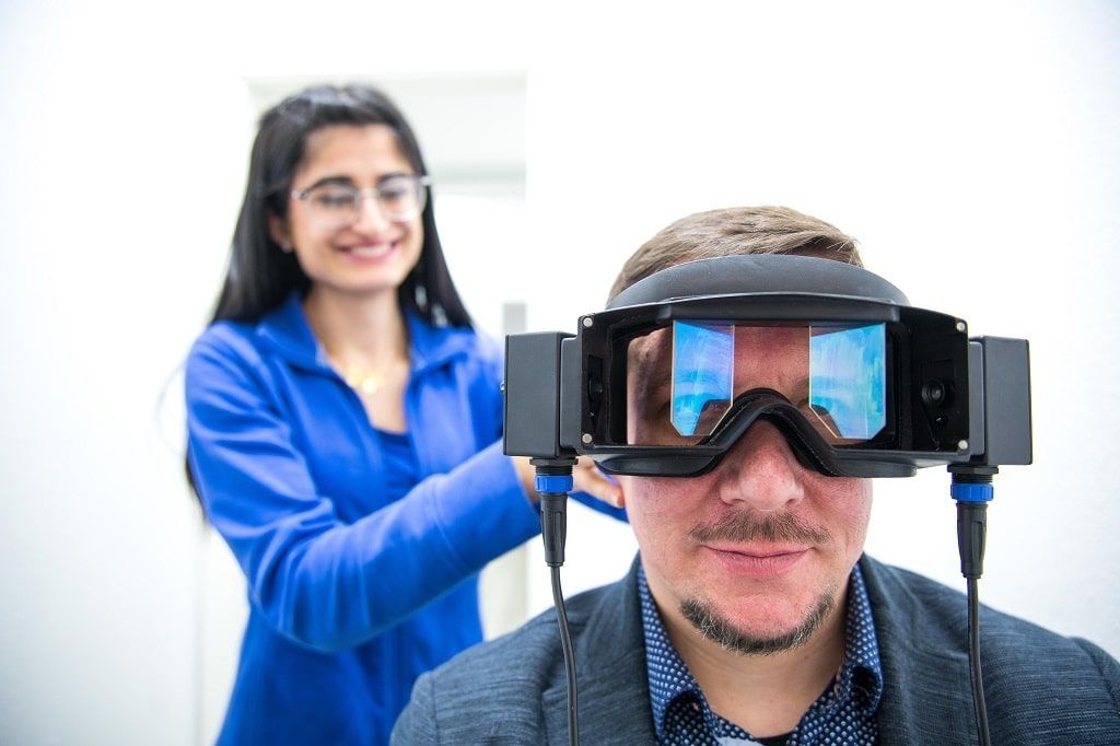 Eine Frau hilft einem Mann dabei, ein Virtual-Reality-Headset aufzusetzen.