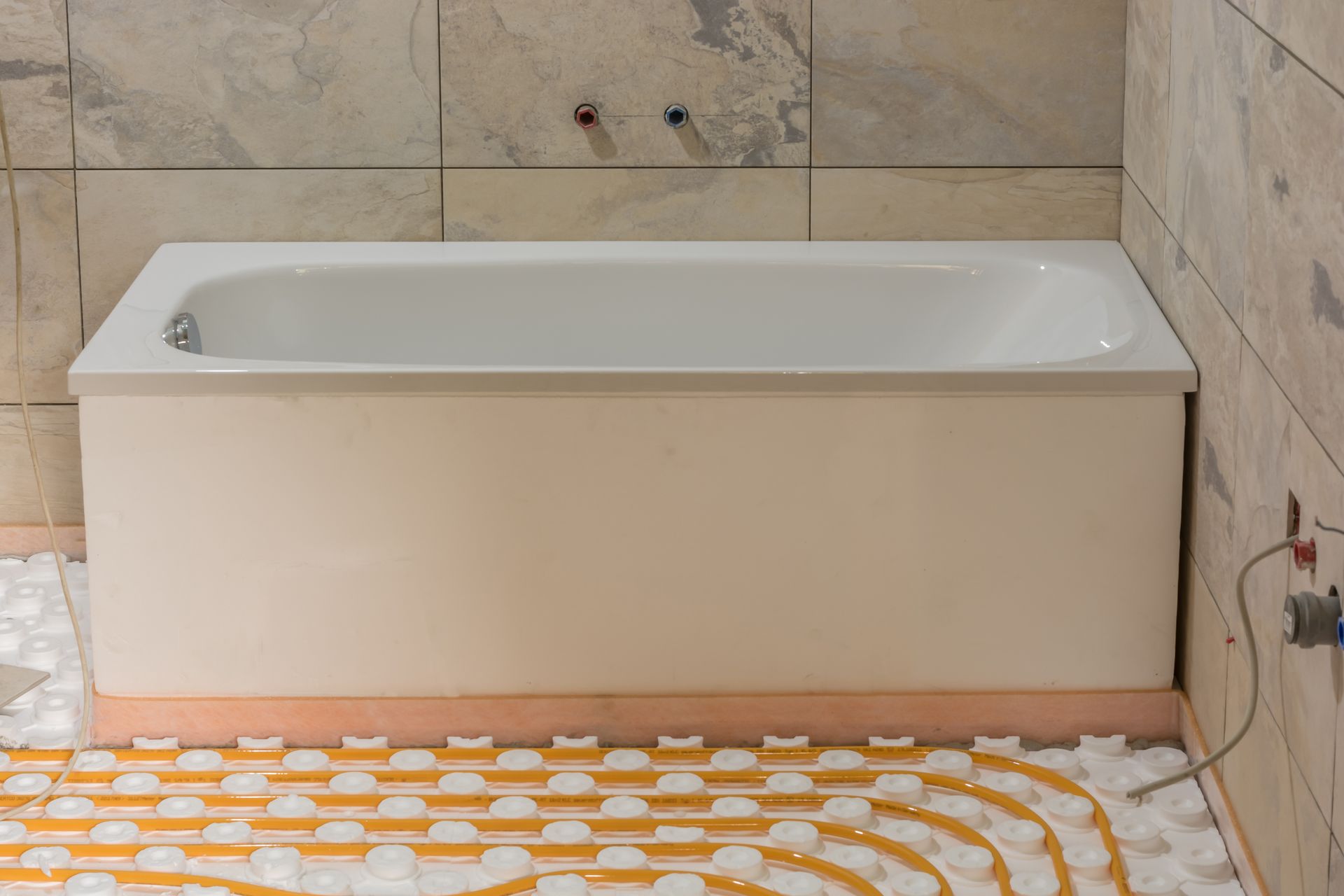 Baignoire dans une salle de bains, un circuit de chauffage au sol en cours d'installation.