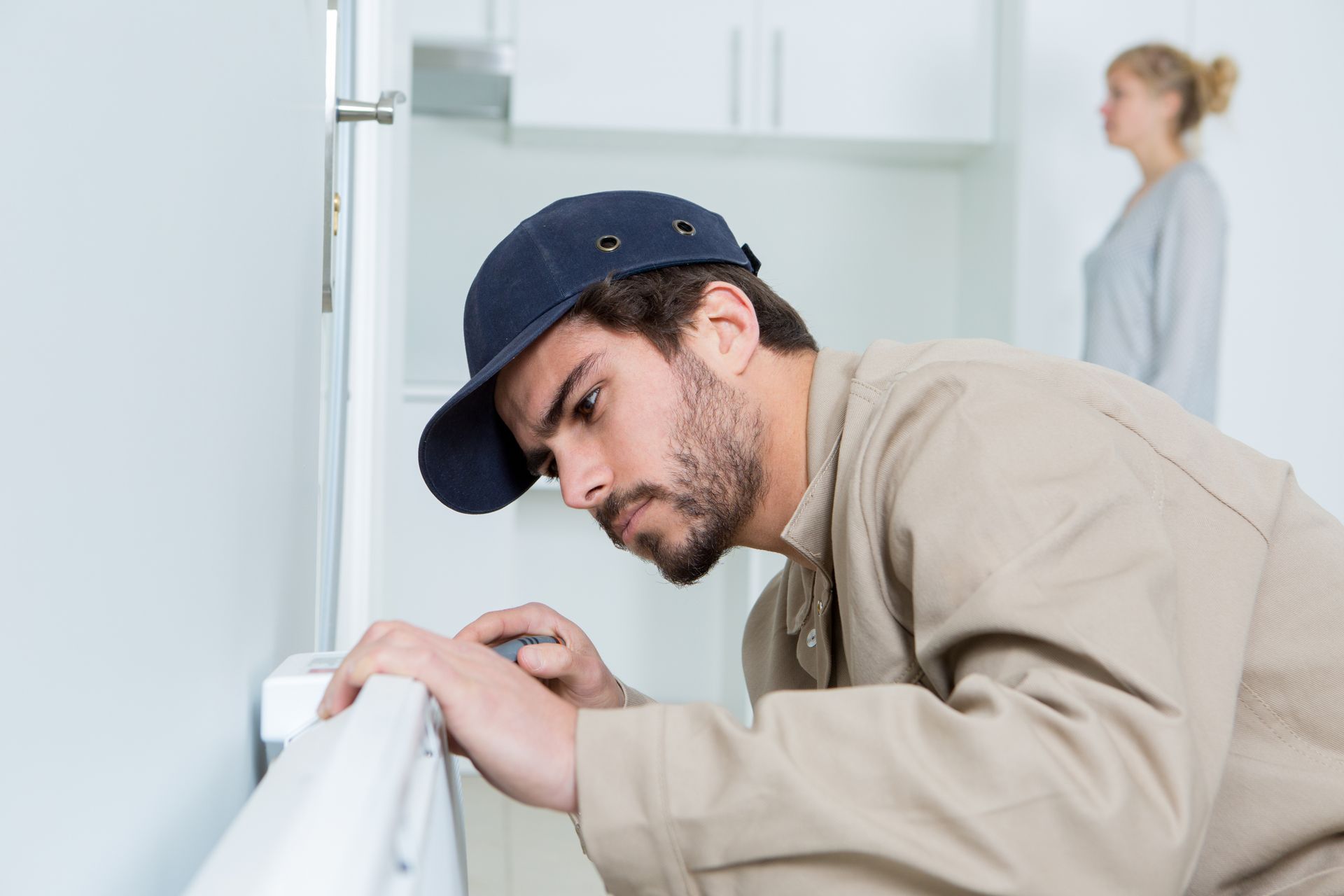 Un homme en tenue de travail inspecte un radiateur.