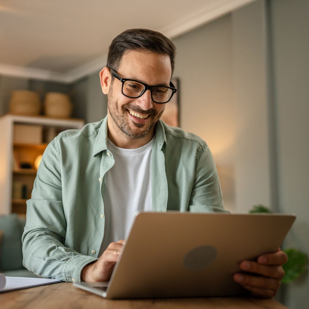 Un homme souriant qui consulte son ordinateur.