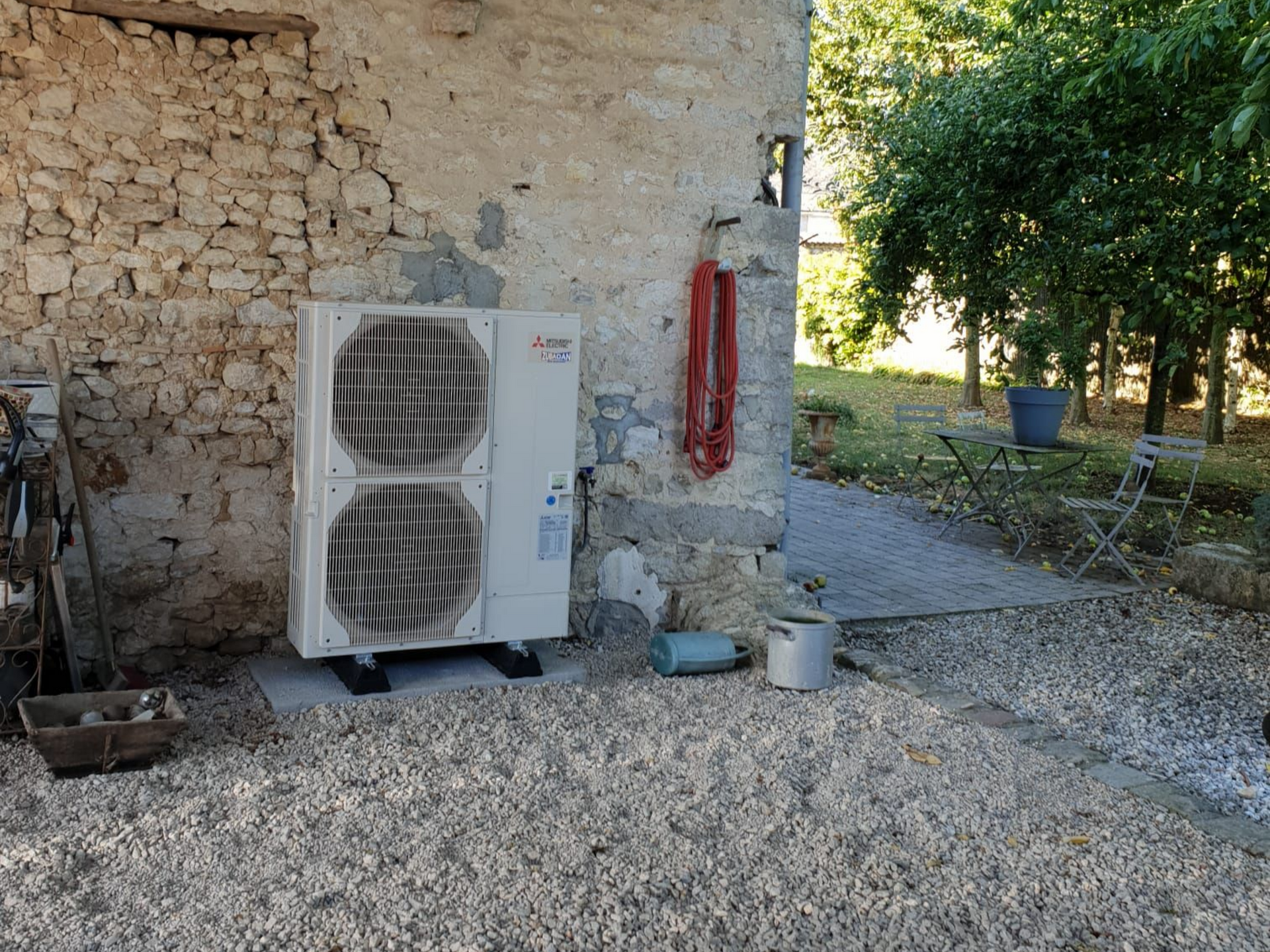 Une unité extérieure de pompe à chaleur adossée à un mur en pierre.