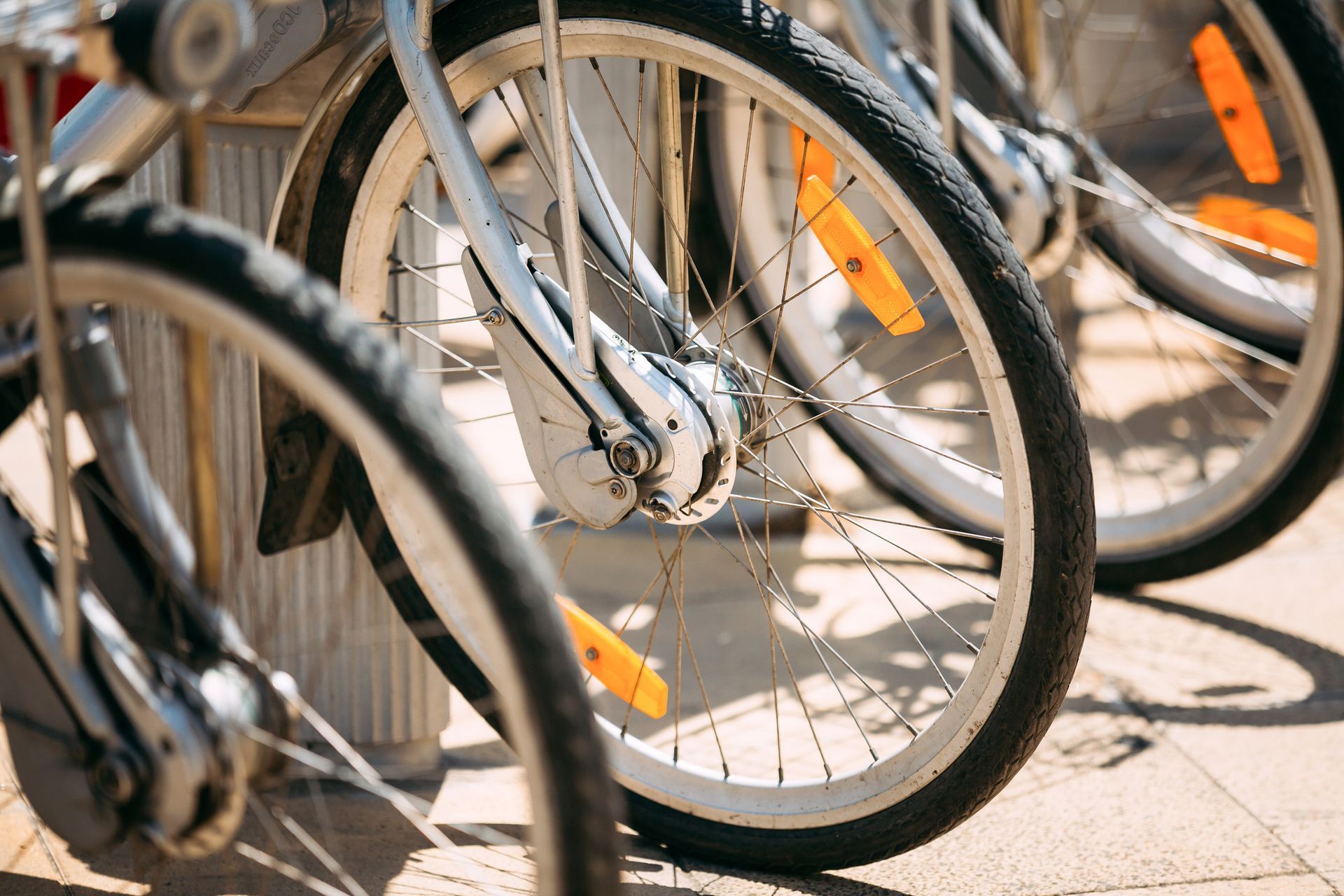 Primer plano de ruedas de bicicleta con reflectores de seguridad; estacionadas sobre una superficie de ladrillo.