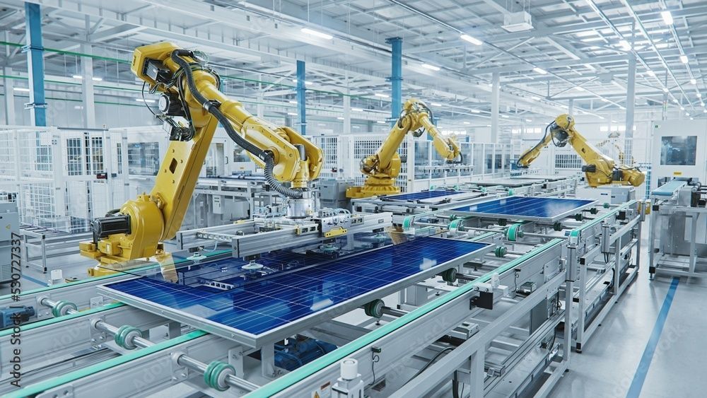 Bracci robotici assemblano pannelli solari blu sulla catena di montaggio di una fabbrica.