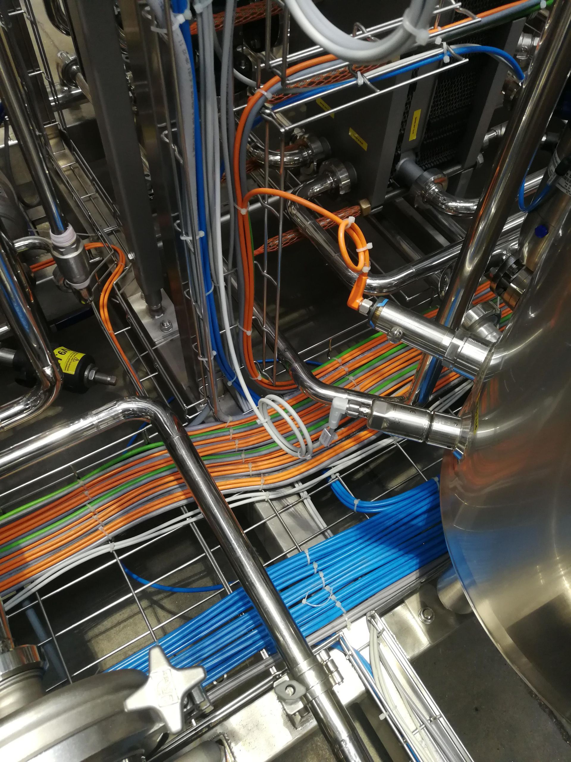 Interno di una fabbrica: bracci robotici, macchinari e attrezzature in un ambiente industriale luminoso.