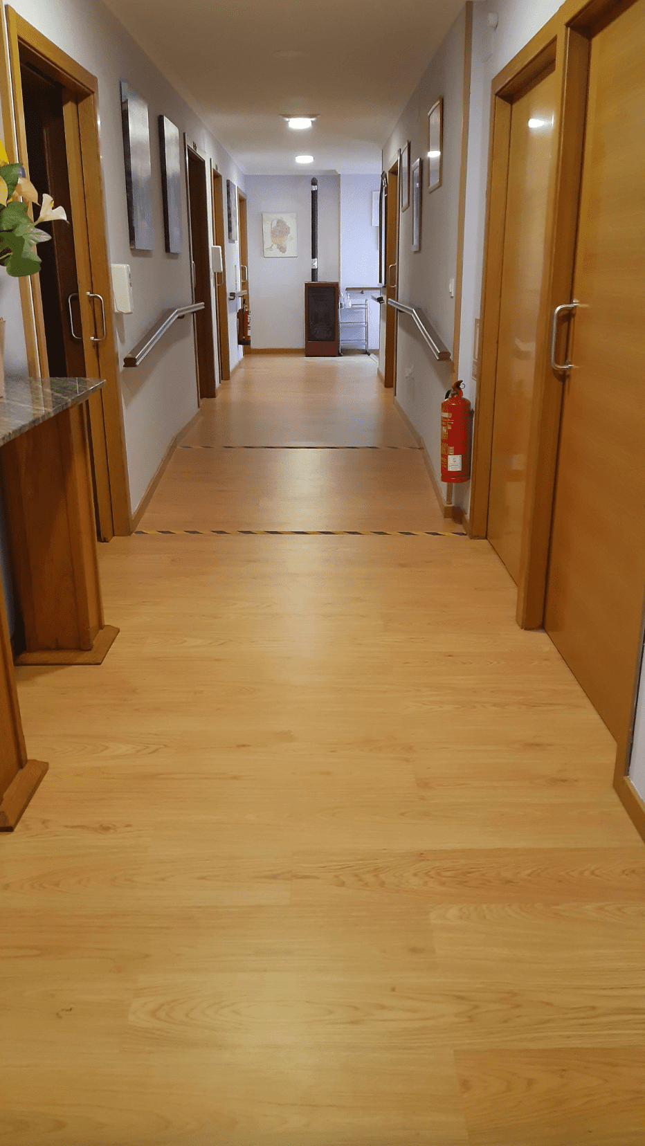 Un pasillo largo con pisos y puertas de madera en un edificio.