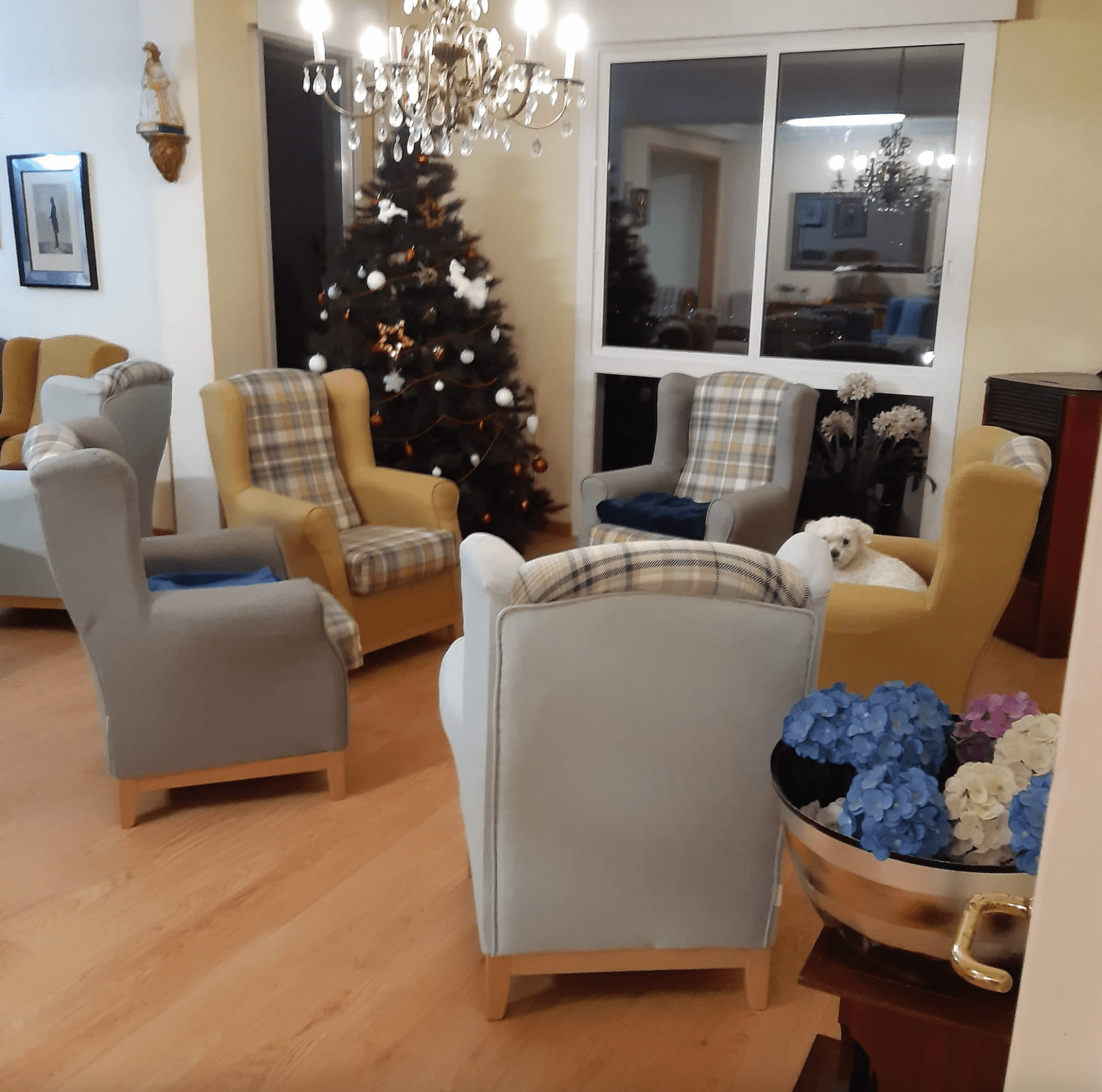 Una sala de estar con sillas y un árbol de Navidad al fondo.