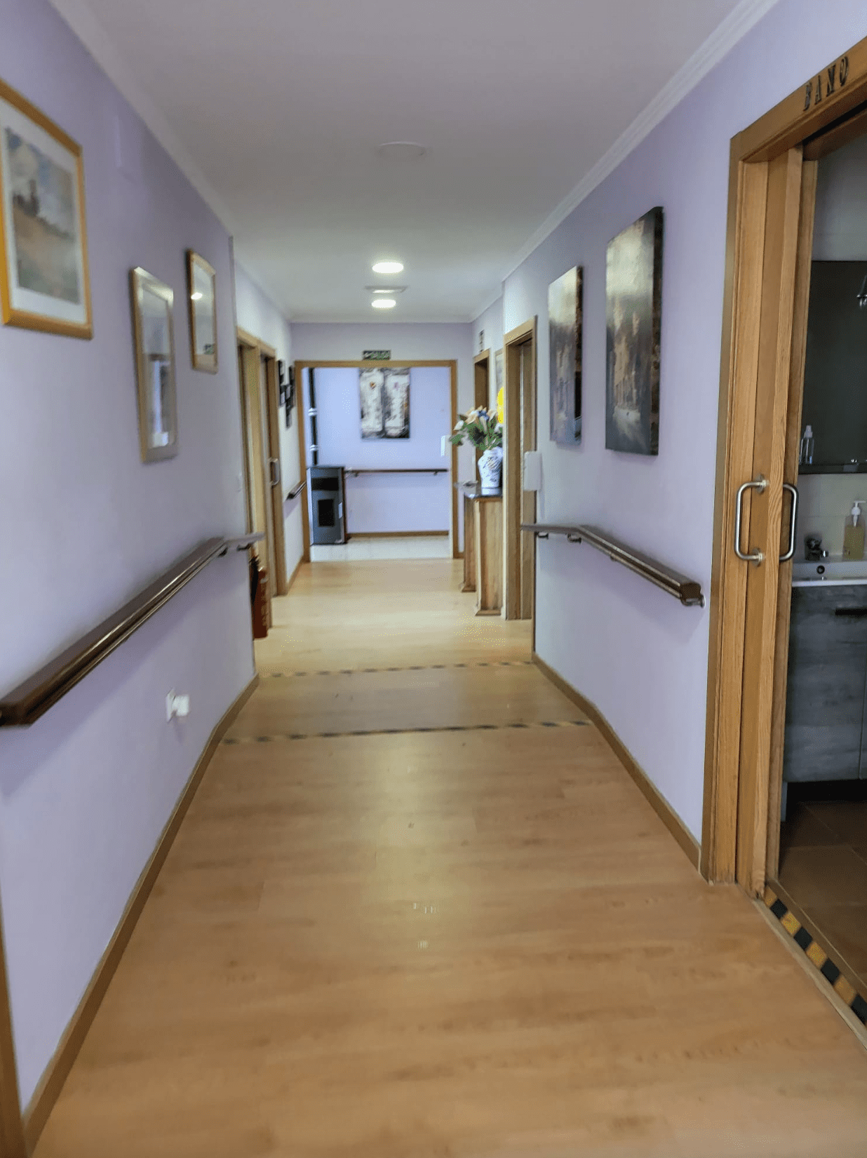 Un largo pasillo con paredes moradas y suelos de madera.