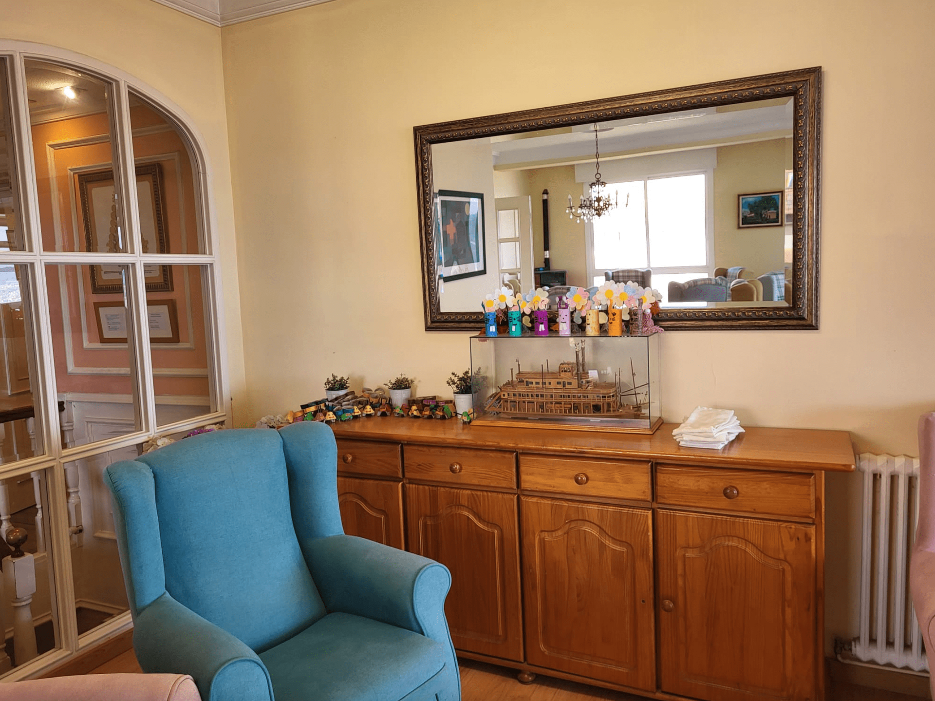 Una sala de estar con una silla azul y un espejo grande.