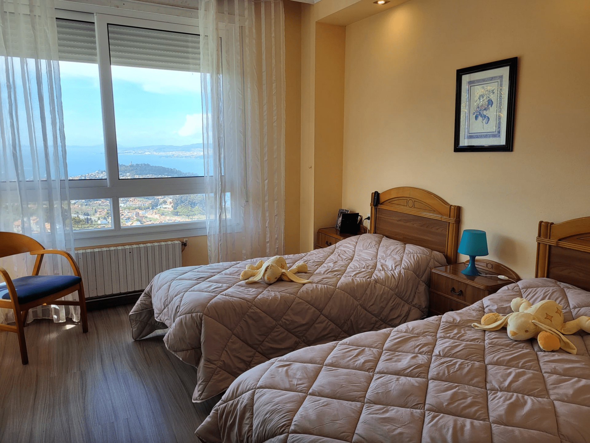 Un dormitorio con dos camas, una silla y una ventana.