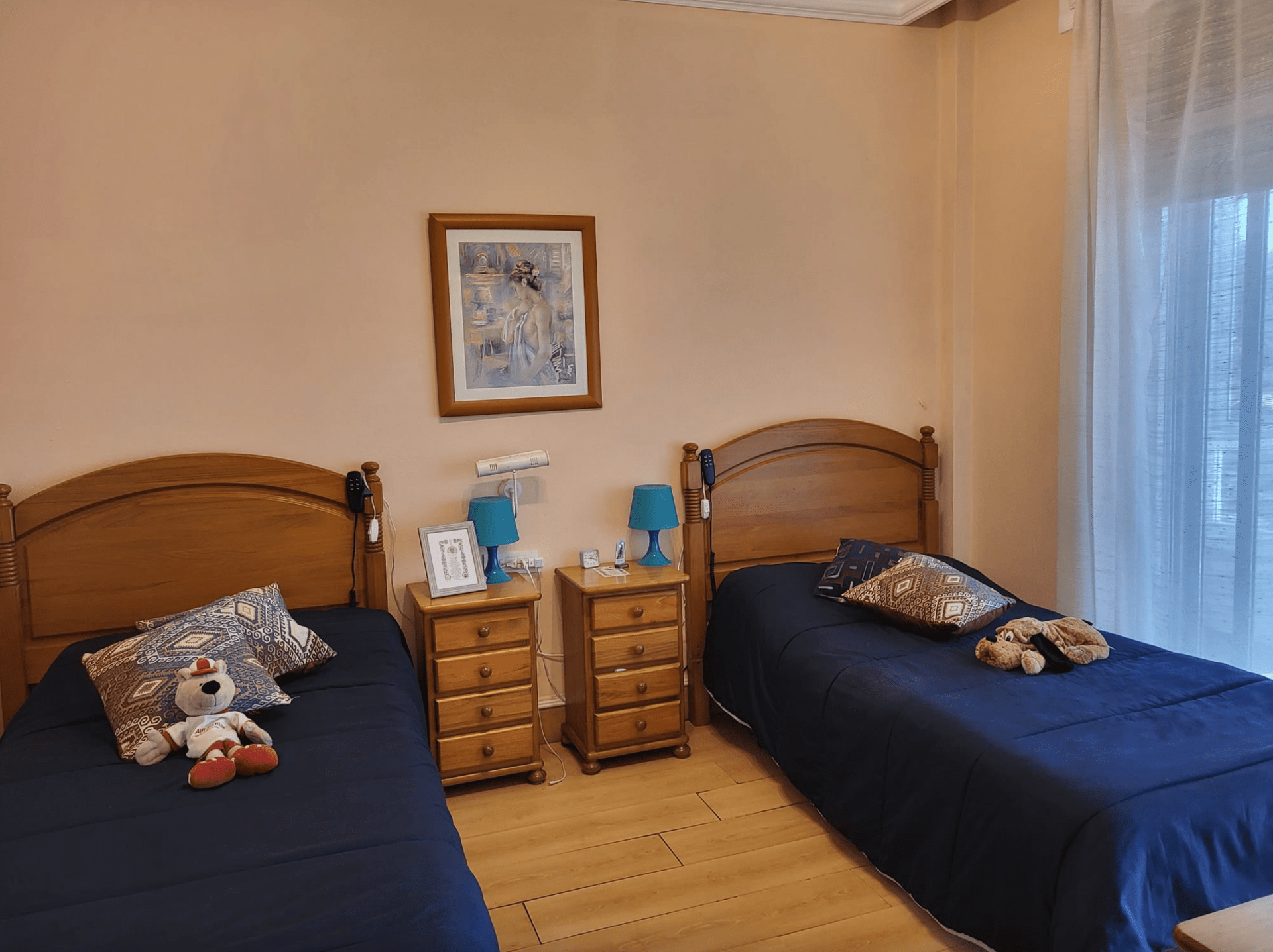 Un dormitorio con dos camas, dos mesitas de noche y un cuadro en la pared.