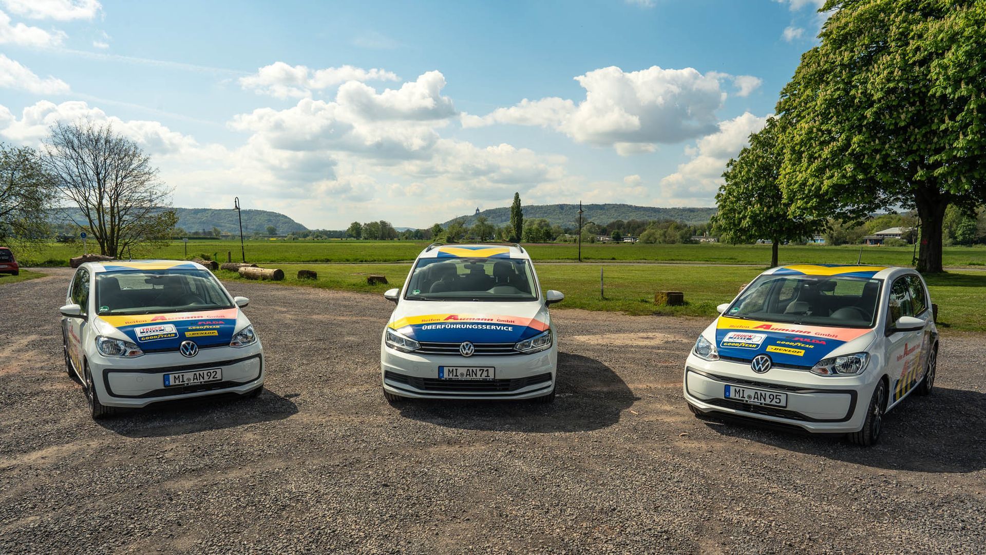Auf einem Schotterplatz sind drei Autos nebeneinander geparkt.