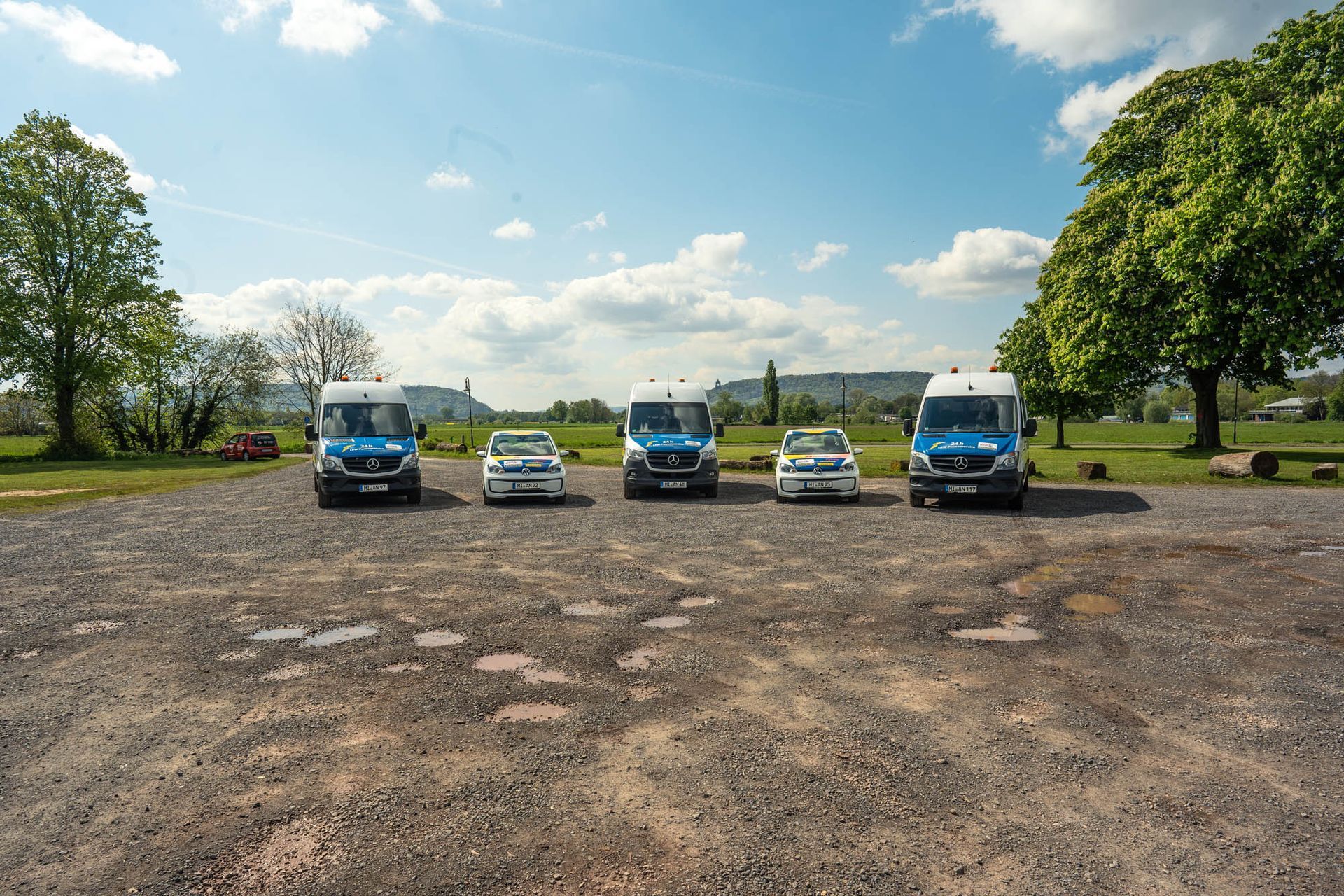 Eine Reihe blau - weißer Lieferwagen steht auf einem Schotterplatz.