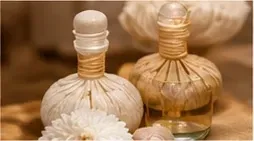 Dos frascos de perfume de vidrio ámbar con flores blancas sobre un fondo beige