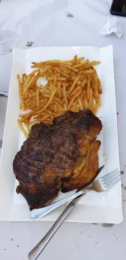 Un plato blanco cubierto con un filete y papas fritas.