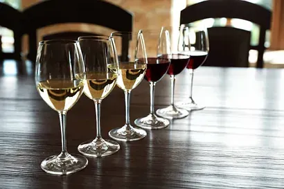 Una fila de copas de vino están alineadas sobre una mesa de madera.