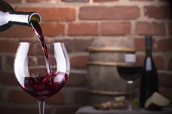 Se vierte una botella de vino tinto en una copa.