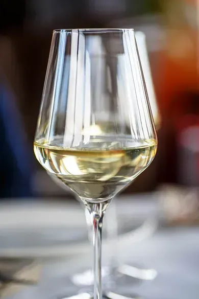 Una copa de vino blanco está sobre una mesa.