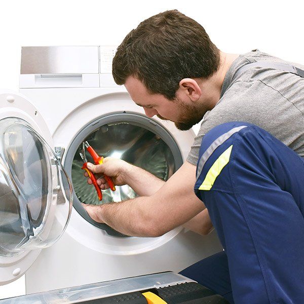 Un dépanneur qui tente de réparer une machine à laver