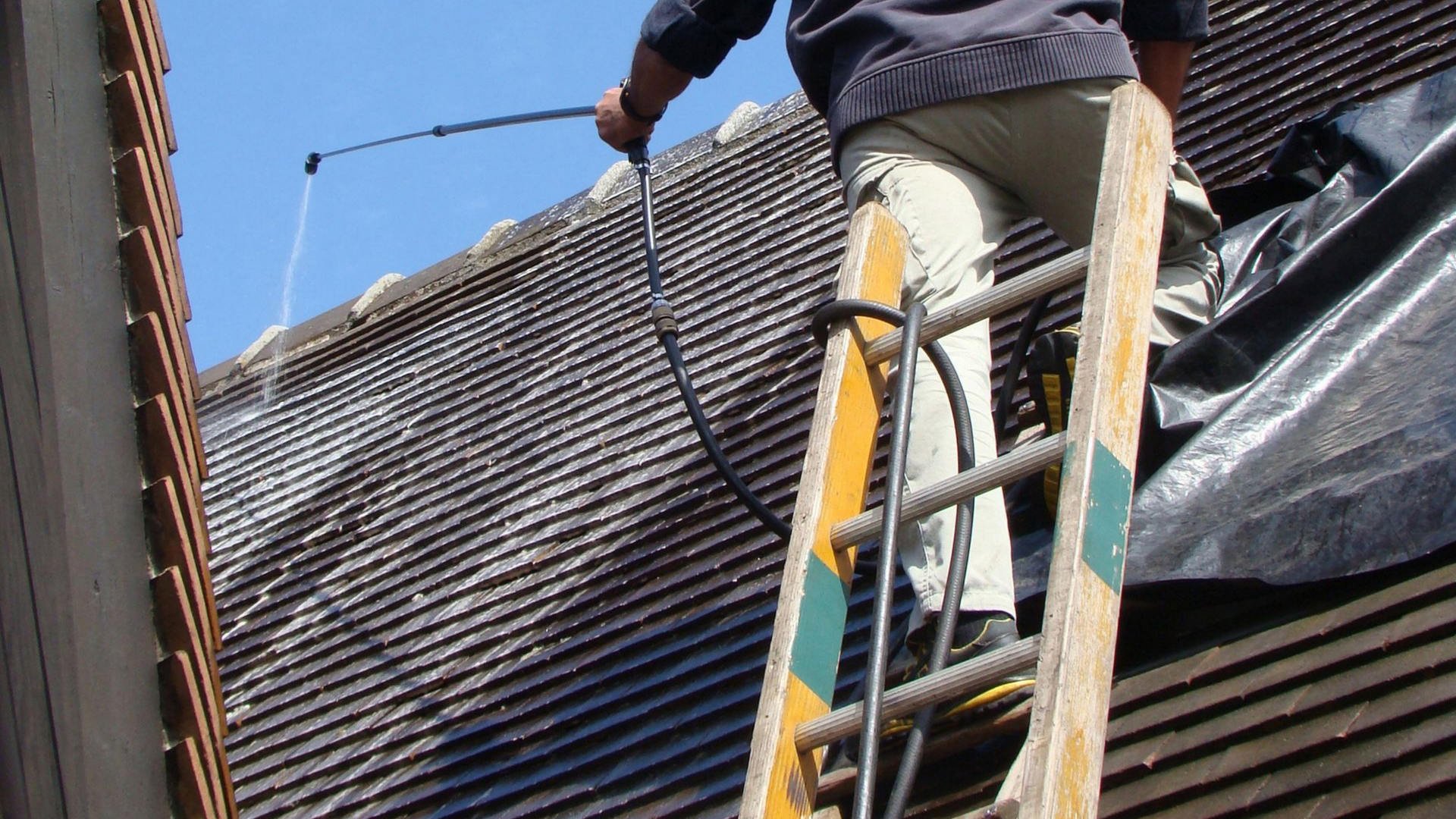 Une personne pulvérisant un produit sur un toit.