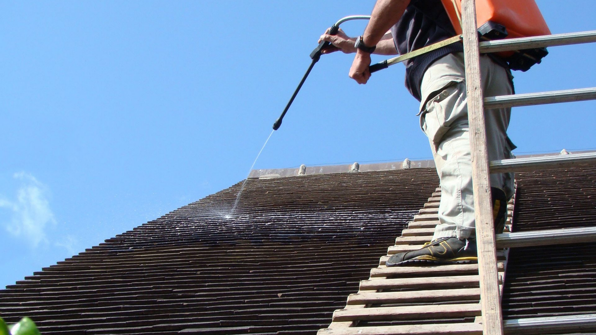 Une personne pulvérise du produit sur un toit.