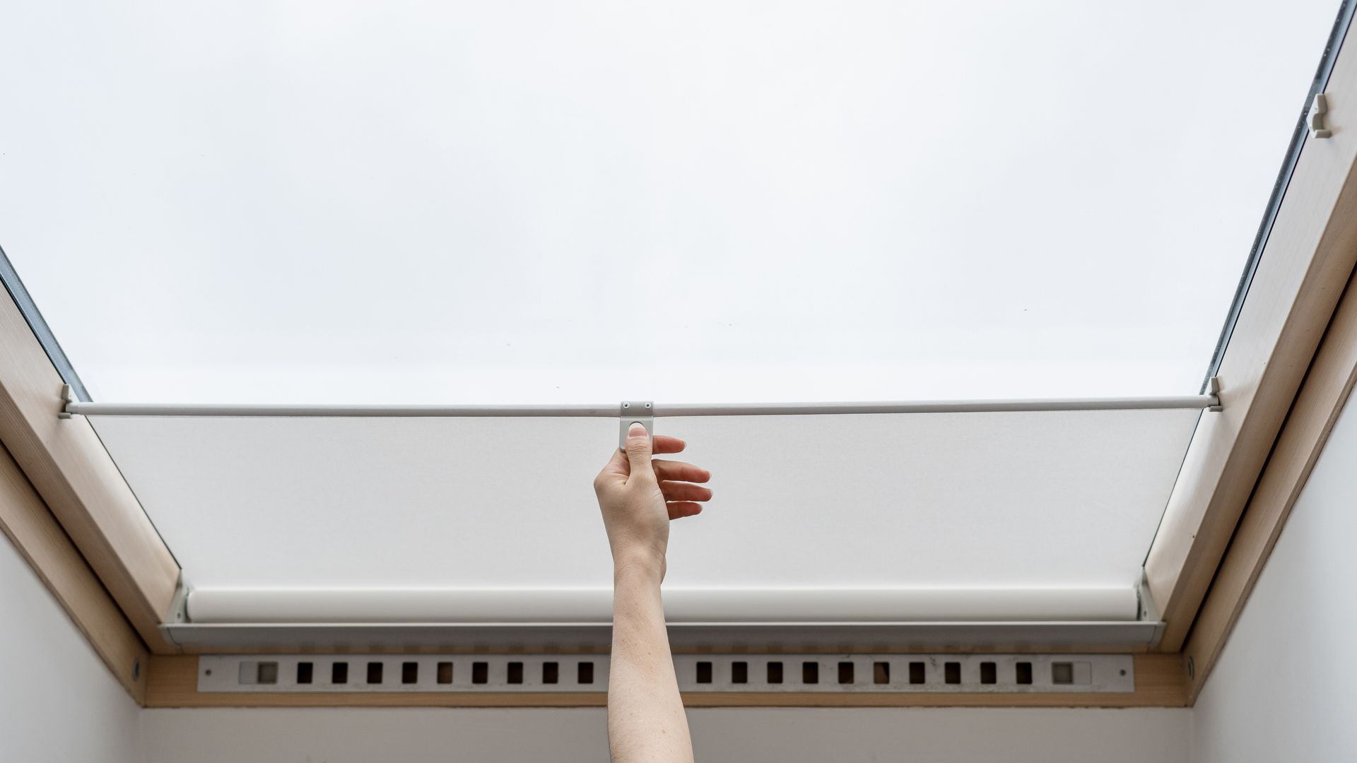 Main tendue pour ouvrir un store de VELUX.