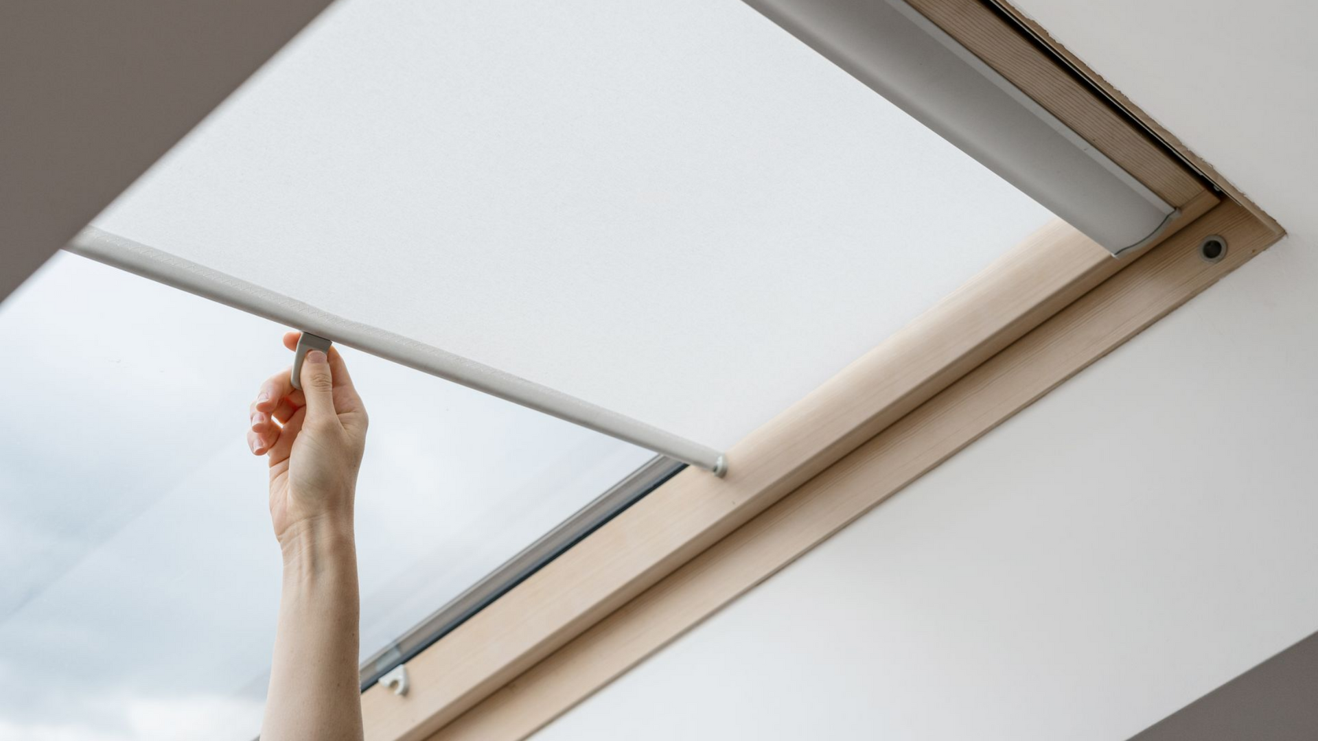 Main ouvrant un store de VELUX.