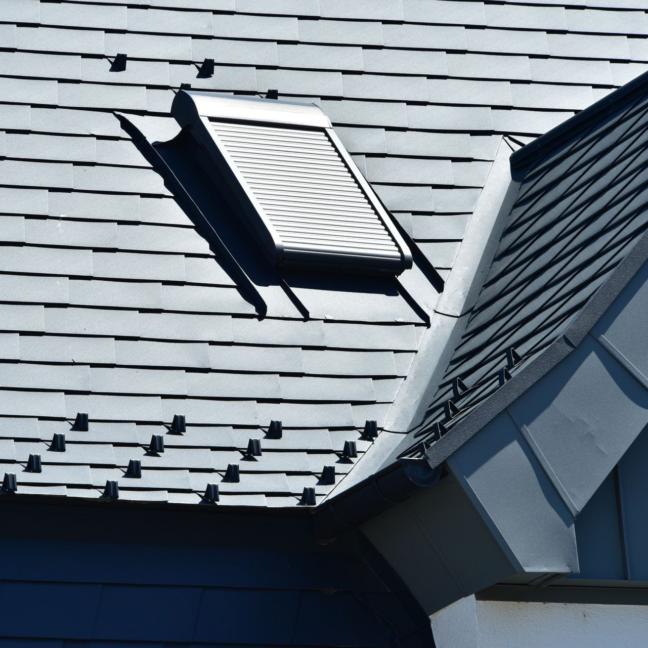 Toiture en ardoises avec un Velux au volet fermé.