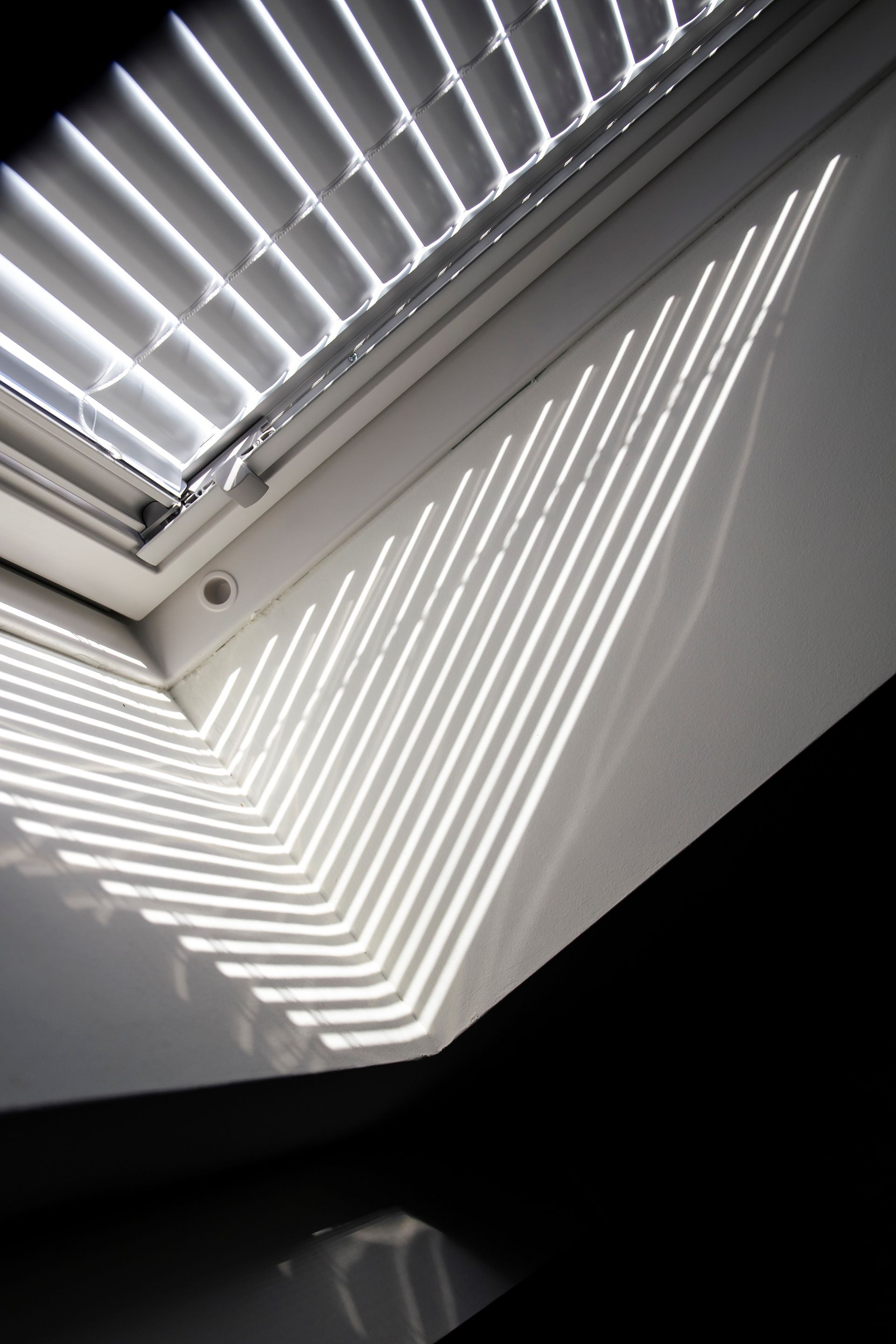 La lumière du soleil traverse une fenêtre avec un store.