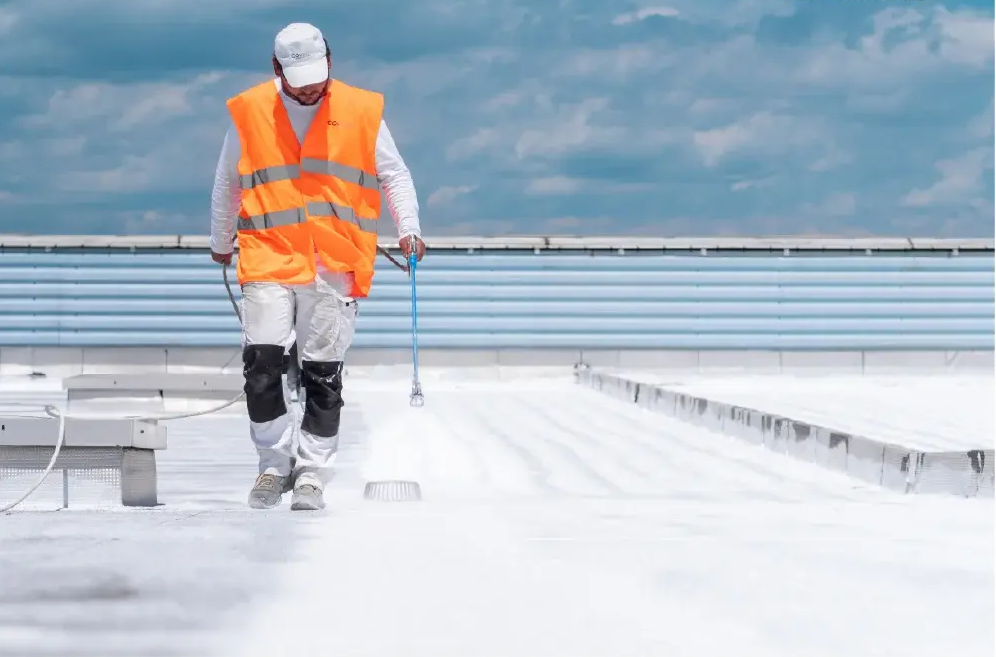 Un homme sur un toit plat effectue de l'isolation par Cool Roof