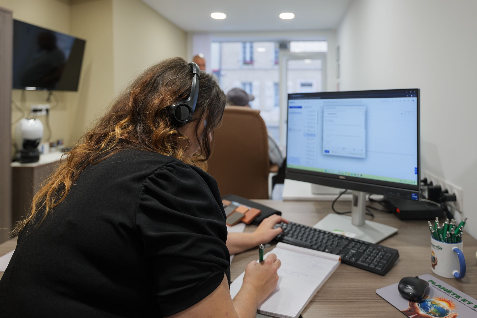 Une femme assise devant un ordinateur, portant un casque