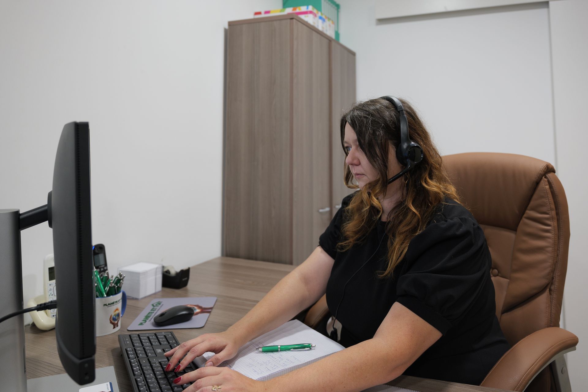 Une femme portant un casque, assise devant un ordinateur