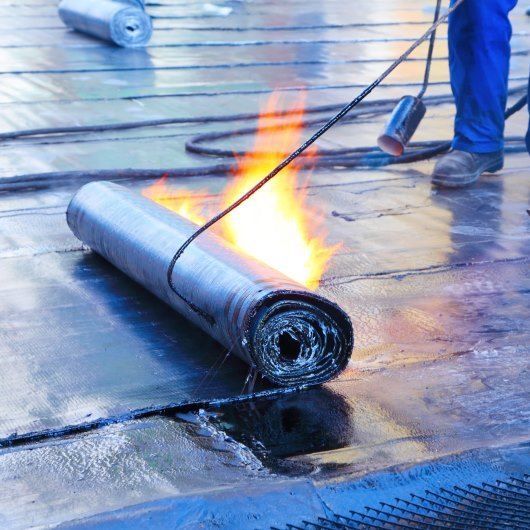 Un homme sur un toit plat installe une membrane d'étanchéité