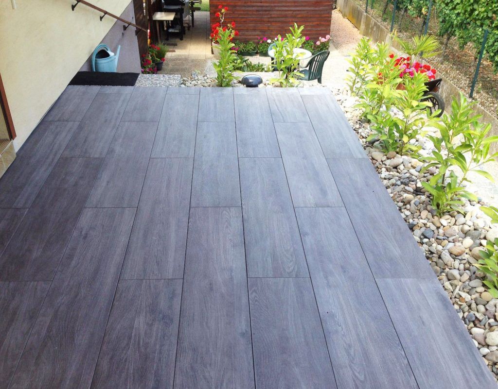 Dallage en pierre d'une terrasse de maison individuelle bordée par des plantations