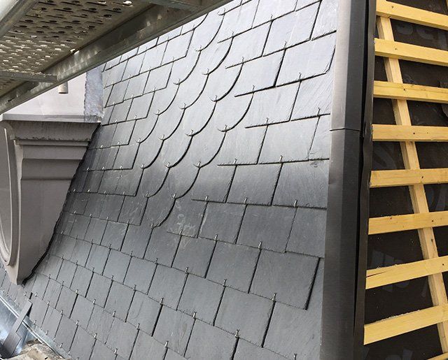 Toiture recouverte de tuiles en ardoise en cours de pose