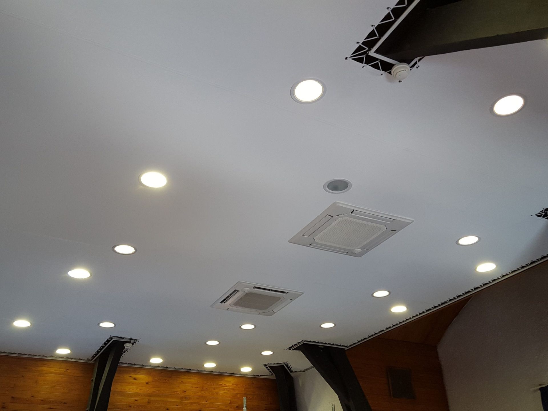 Plafond blanc avec spots encastrés et deux climatiseurs.