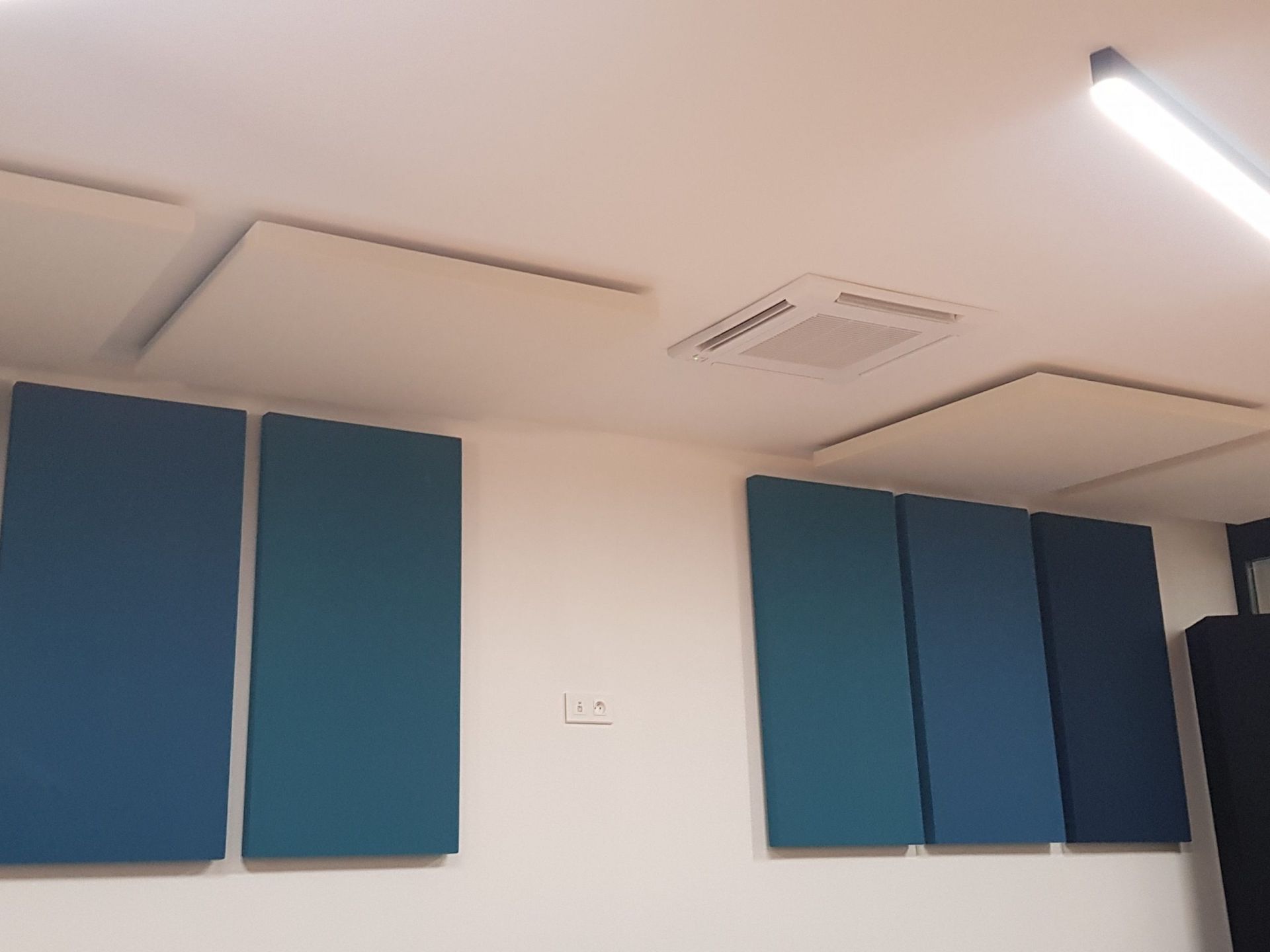 Panneaux acoustiques bleus et blancs sur les murs et le plafond d'une pièce.