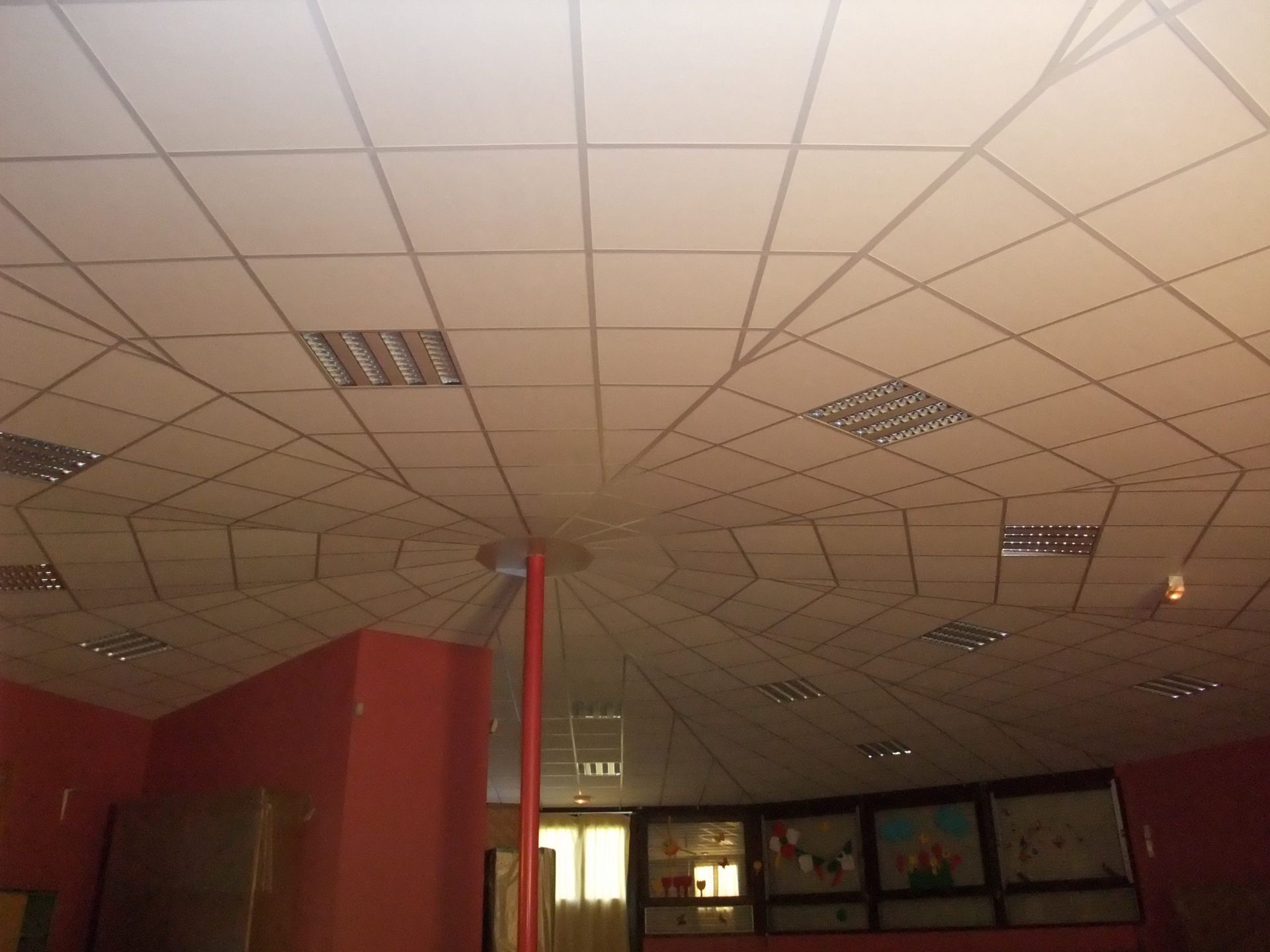 Plafond avec motif quadrillé, spots encastrés et murs rouges.