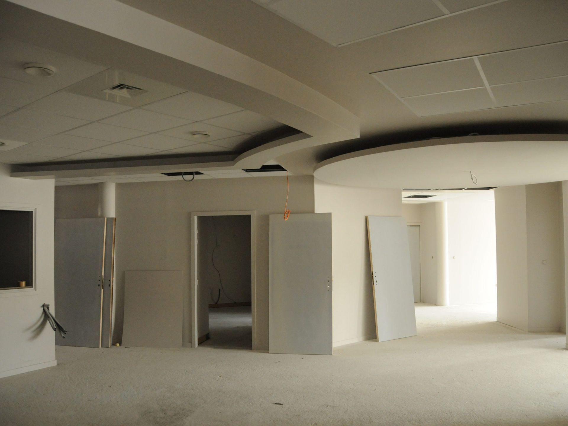 Un espace intérieur inachevé avec des murs, des portes et des détails de plafond blancs.