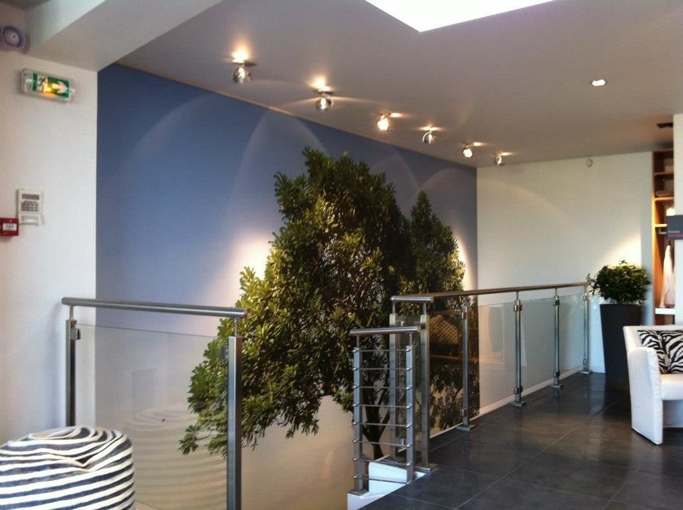 Couloir intérieur avec une fresque d'arbres, des balustrades en verre et des spots.