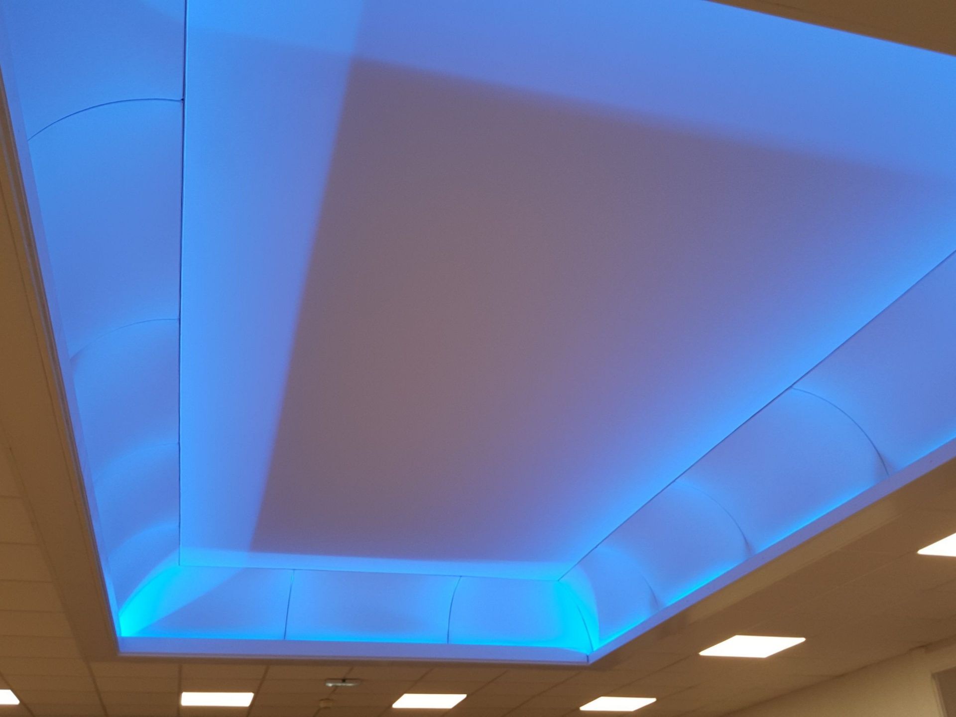 Plafond avec zone encastrée éclairée par des lumières bleues.